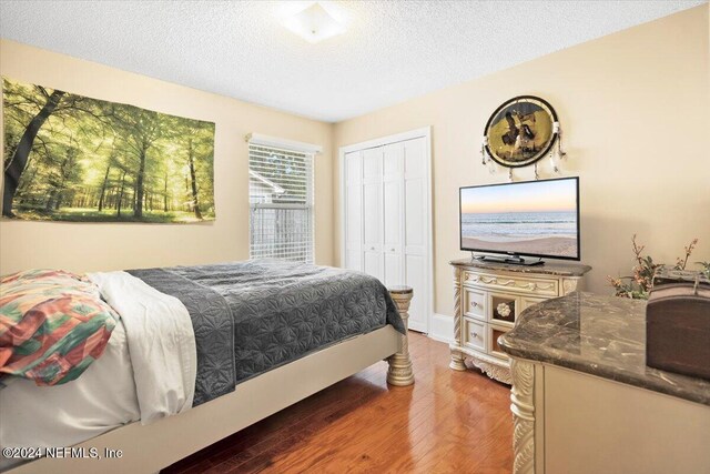 bedroom with hardwood / wood-style floors, a textured ceiling, and a closet