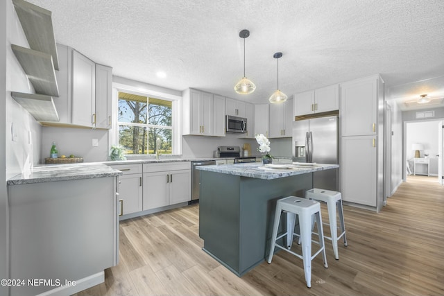 kitchen with white cabinets, light wood-type flooring, stainless steel appliances, and a kitchen island