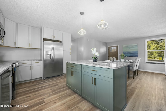 kitchen featuring white cabinets, appliances with stainless steel finishes, and hanging light fixtures