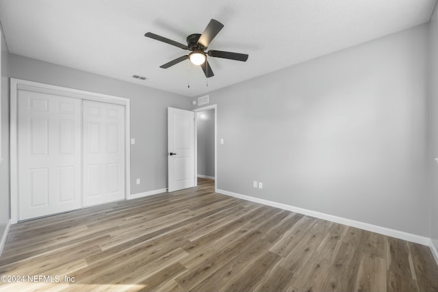 unfurnished bedroom featuring ceiling fan, wood-type flooring, and a closet