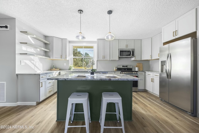 kitchen featuring dark stone counters, a kitchen breakfast bar, light hardwood / wood-style flooring, a kitchen island, and stainless steel appliances