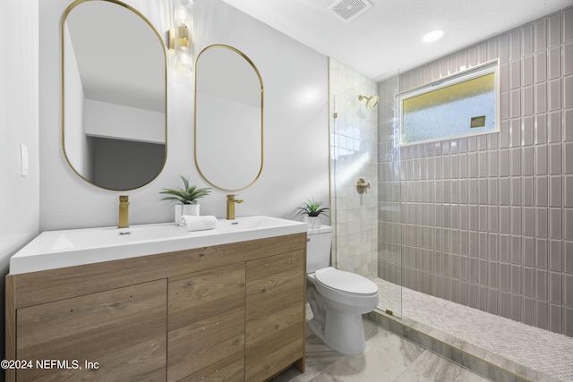 bathroom featuring vanity, toilet, and a tile shower