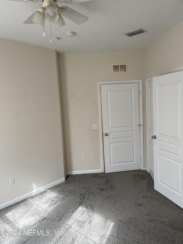 unfurnished room featuring ceiling fan and dark carpet