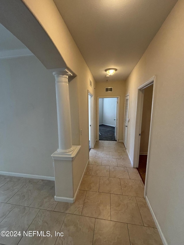 hallway with light tile patterned floors and ornate columns