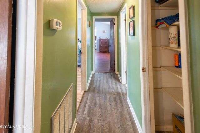 hallway featuring wood-type flooring and a textured ceiling