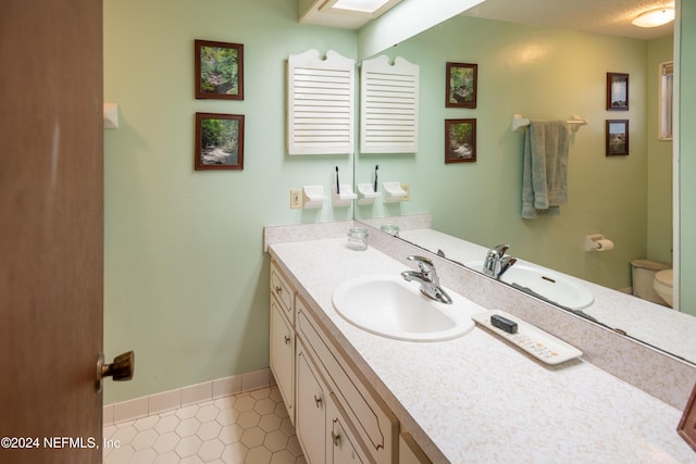 bathroom with tile patterned flooring, vanity, and toilet