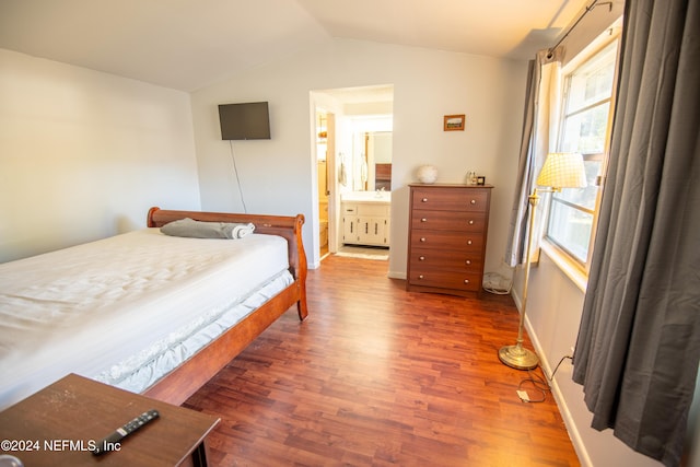 bedroom featuring wood-type flooring, ensuite bathroom, and lofted ceiling