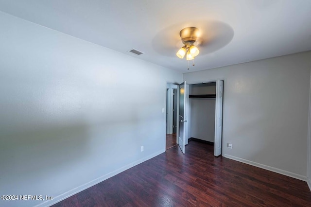 unfurnished bedroom featuring dark wood-type flooring, ceiling fan, and a closet