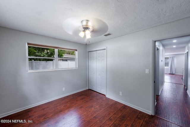 unfurnished bedroom with dark hardwood / wood-style floors, a textured ceiling, ceiling fan, and a closet