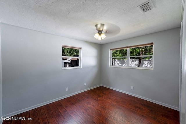 empty room featuring dark wood-type flooring, ceiling fan, plenty of natural light, and a textured ceiling