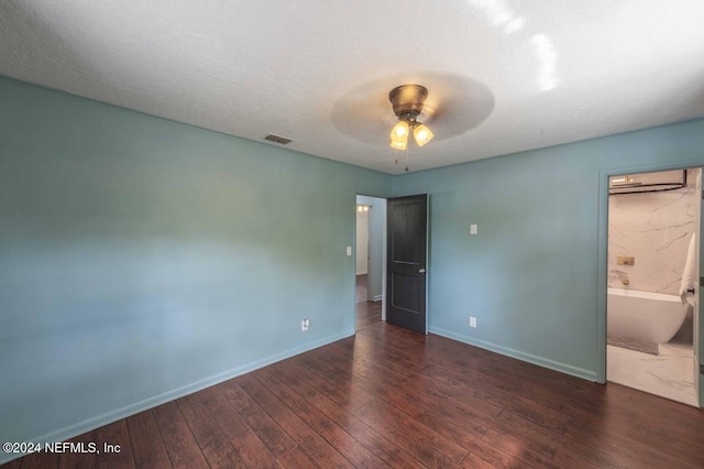 unfurnished bedroom with dark wood-type flooring, connected bathroom, a textured ceiling, and ceiling fan