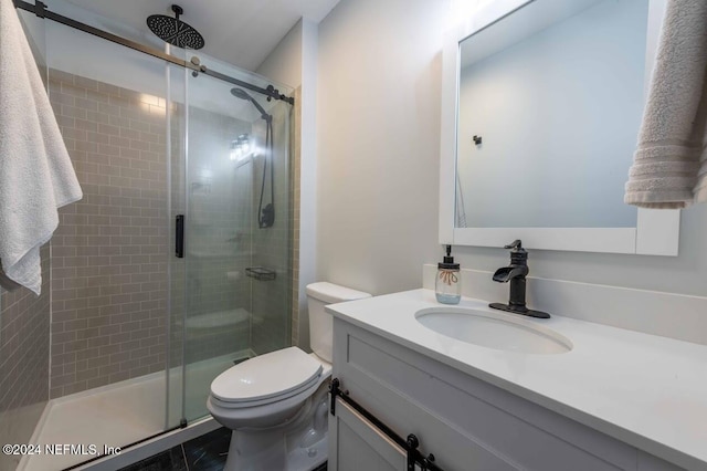 bathroom featuring vanity, a shower with shower door, and toilet