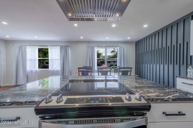 kitchen with crown molding, dark stone counters, stainless steel electric range, and white cabinets