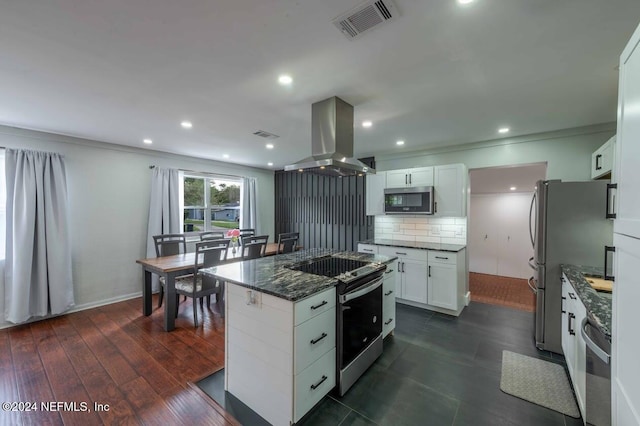 kitchen with stainless steel appliances, island range hood, white cabinets, and dark stone counters