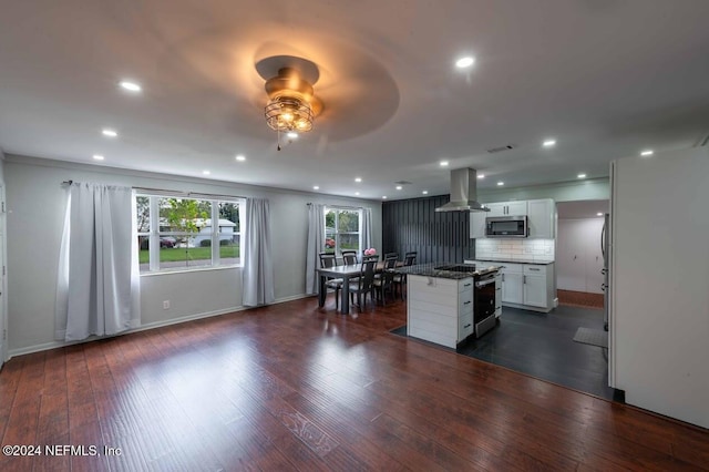 kitchen featuring a kitchen island, white cabinetry, decorative backsplash, island exhaust hood, and stainless steel appliances