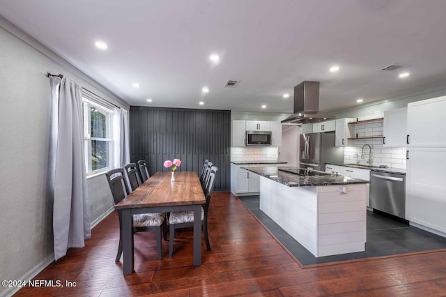 kitchen featuring tasteful backsplash, island range hood, a kitchen island, stainless steel appliances, and white cabinets