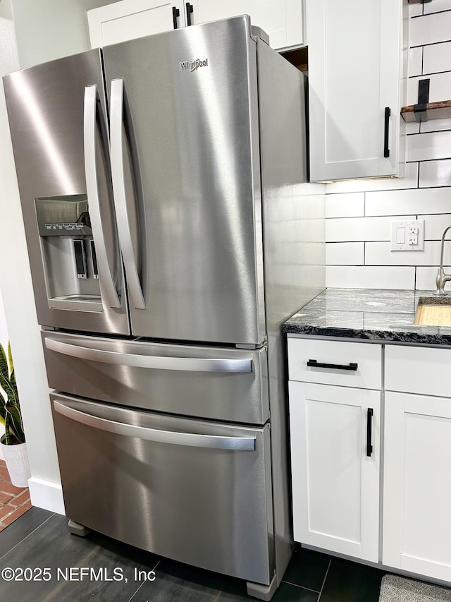 kitchen featuring tasteful backsplash, white cabinetry, sink, dark stone counters, and stainless steel refrigerator with ice dispenser