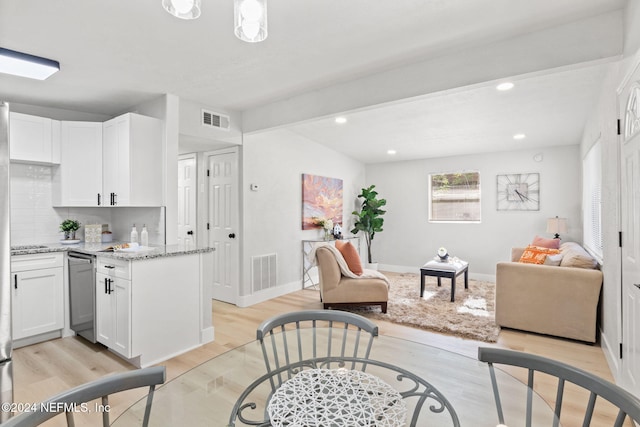 interior space featuring backsplash, white cabinetry, light stone counters, and light wood-type flooring