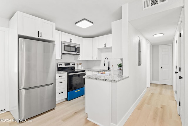 kitchen with light stone countertops, stainless steel appliances, white cabinets, and sink