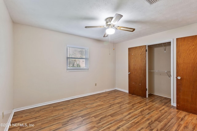 unfurnished bedroom with ceiling fan, wood-type flooring, a textured ceiling, and a closet