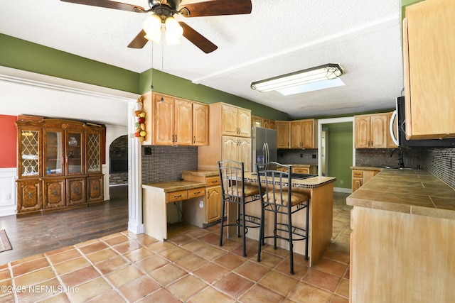 kitchen featuring a sink, decorative backsplash, appliances with stainless steel finishes, and a breakfast bar