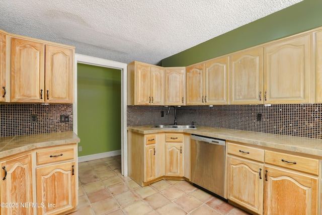 kitchen with light brown cabinetry, light countertops, decorative backsplash, stainless steel dishwasher, and a sink