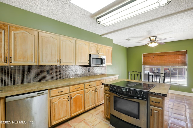 kitchen featuring a ceiling fan, light brown cabinetry, tasteful backsplash, a textured ceiling, and appliances with stainless steel finishes