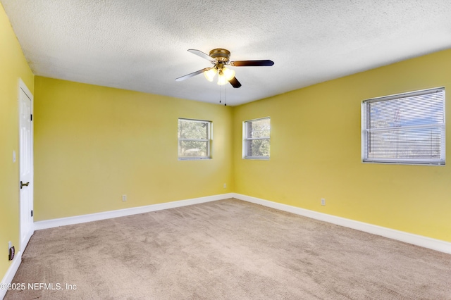 carpeted empty room featuring a textured ceiling, baseboards, and ceiling fan