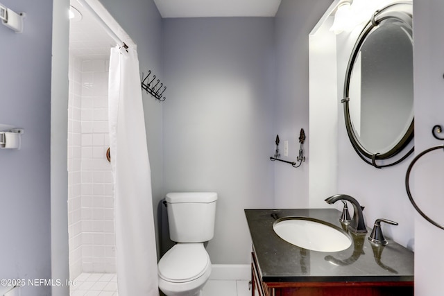 bathroom featuring tiled shower, toilet, vanity, and baseboards