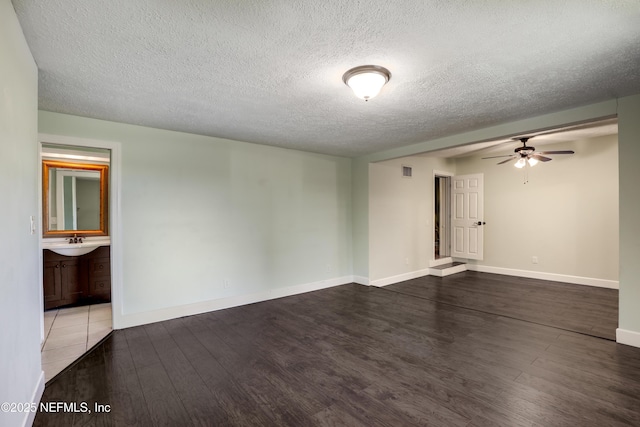 unfurnished room with visible vents, a ceiling fan, a sink, wood finished floors, and baseboards