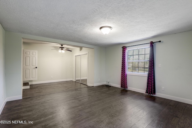 unfurnished room with a textured ceiling, baseboards, dark wood-style flooring, and ceiling fan