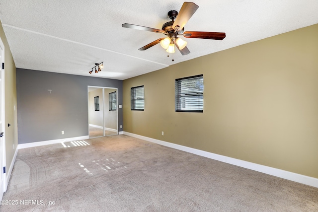 unfurnished room featuring baseboards, carpet flooring, a textured ceiling, and ceiling fan