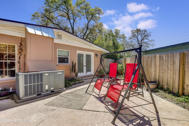 view of patio featuring french doors, central AC unit, and fence