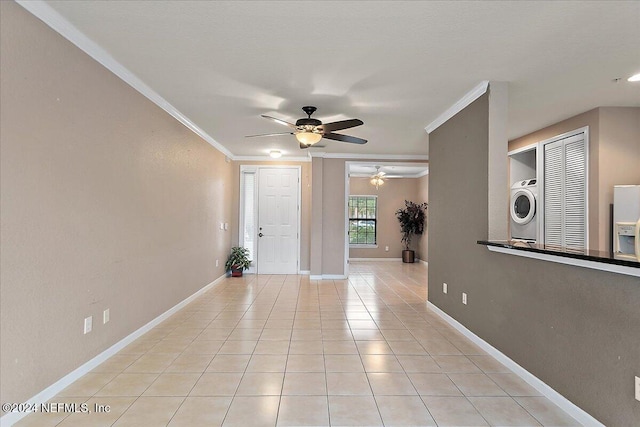 tiled entryway with ceiling fan, stacked washer / drying machine, and ornamental molding