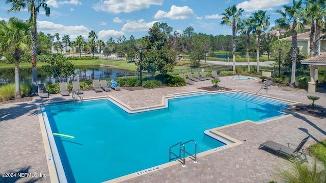 view of pool with a water view, a hot tub, and a patio area