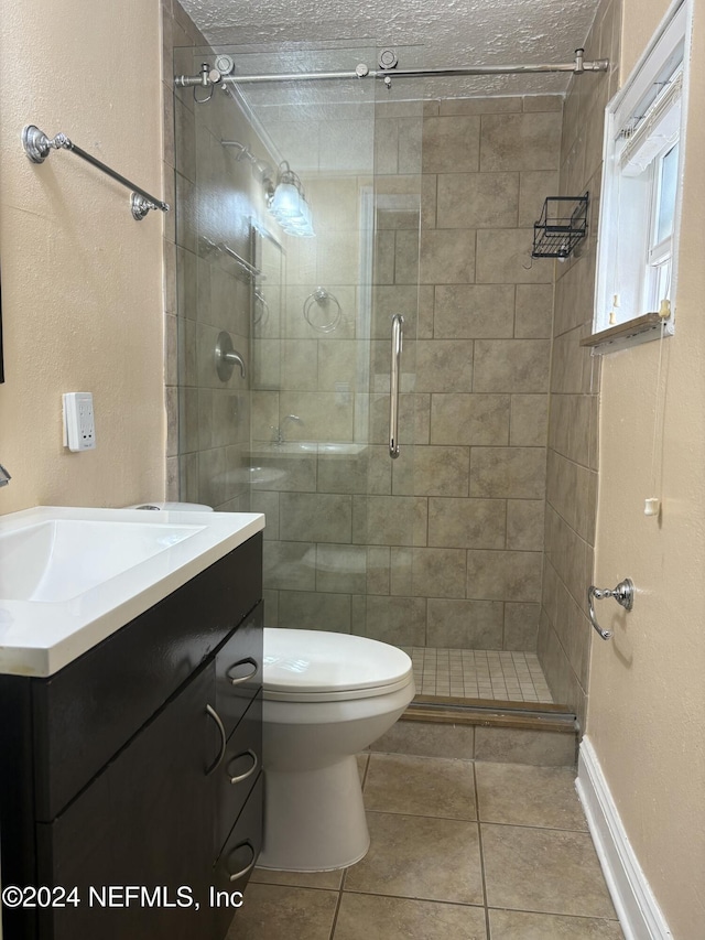 bathroom featuring tile patterned flooring, vanity, a textured ceiling, and toilet