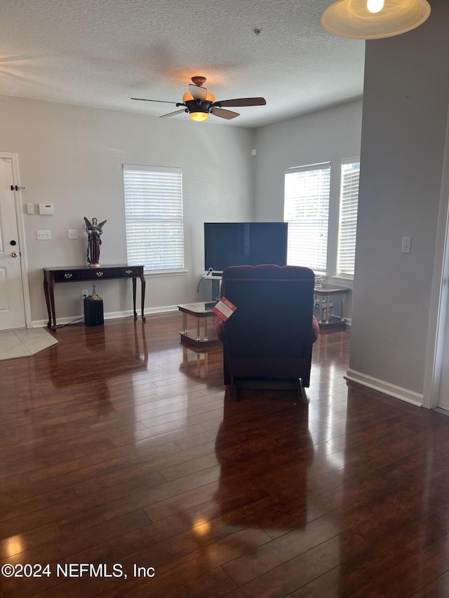 living room featuring a textured ceiling, dark hardwood / wood-style flooring, and ceiling fan