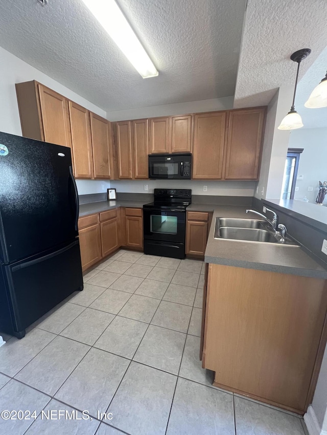 kitchen with sink, a textured ceiling, decorative light fixtures, light tile patterned flooring, and black appliances