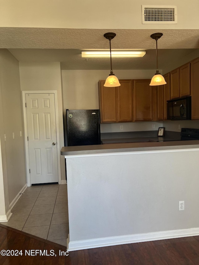 kitchen featuring black appliances, pendant lighting, a textured ceiling, and wood-type flooring