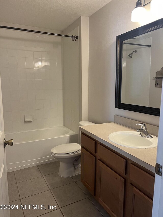 full bathroom with tile patterned floors, vanity, a textured ceiling, toilet, and tiled shower / bath