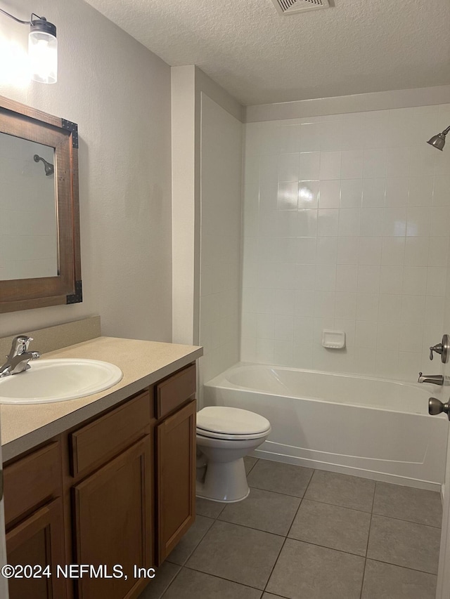 full bathroom with vanity, a textured ceiling, tile patterned flooring, toilet, and tiled shower / bath