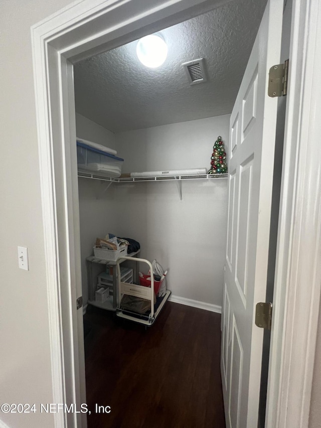 walk in closet with dark hardwood / wood-style floors