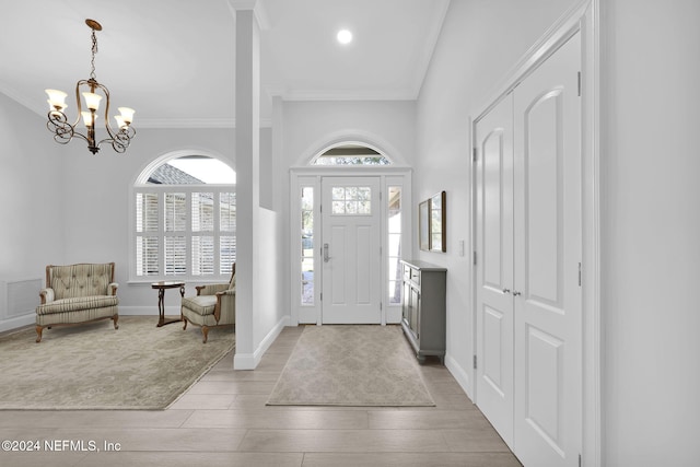 foyer entrance featuring a chandelier, light wood-type flooring, and ornamental molding