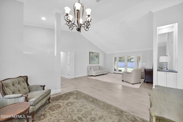 living room featuring a notable chandelier, light wood-type flooring, lofted ceiling, and ornamental molding