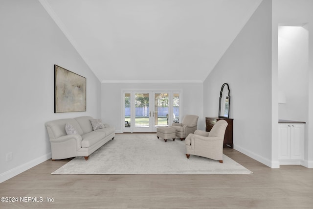 living room featuring light hardwood / wood-style floors, lofted ceiling, crown molding, and french doors