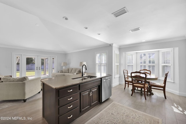 kitchen with light wood-type flooring, stainless steel dishwasher, dark brown cabinetry, sink, and an island with sink