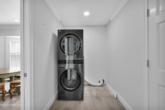 laundry area with stacked washing maching and dryer, hardwood / wood-style flooring, and crown molding