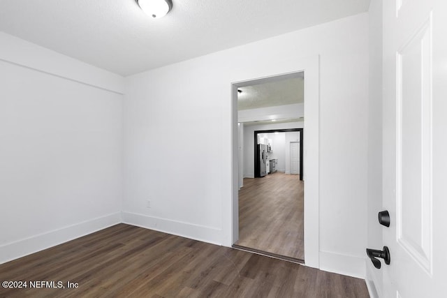 spare room featuring a textured ceiling and dark hardwood / wood-style floors