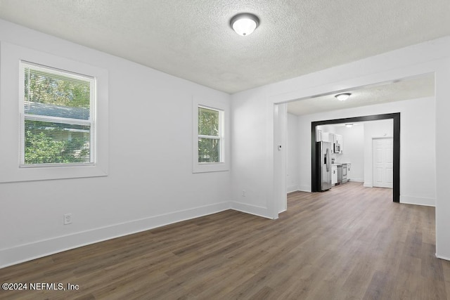 unfurnished room with a textured ceiling and dark wood-type flooring