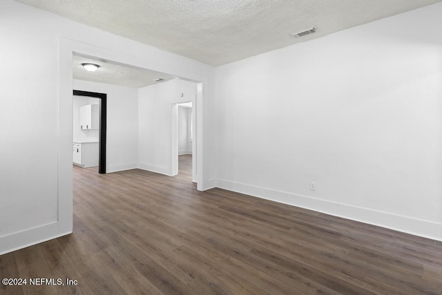 spare room with dark wood-type flooring and a textured ceiling